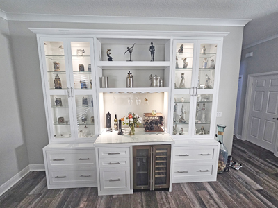Custom Bar and Hutch, Crown Molding, Shaker Drawers, Glass Doors and Shelves with Stemware Holder and Solid Shelves above Wine Fridge is shown in Bright White on Maple with Nickel Bar Pulls