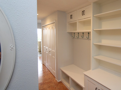 Floor to ceiling custom built-in shaker cabinets with drawers, doors, adjustable shelve with crown molding shown in solid bright white on maple decorated shelves