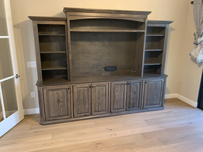 Custom Traditional Entertainment Center with Cleated Shelf above TV shown in Warm Toffee on Oak with Black Round Knobs
