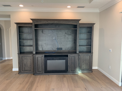 Traditional Entertainment Center with Cleated Shelf above TV and Fireplace Cabinet shown in Warm Toffee on Oak with Black Round Knobs