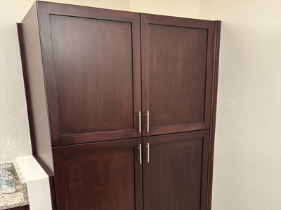 Custom Shaker Bathroom Linen Closet with adjustable shelves and satin nickel pulls shown in Custom Cherry color match on Maple